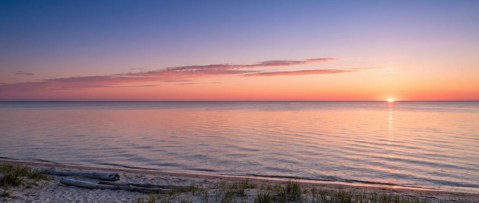 Sunrise over a calm lake and a sandy shore